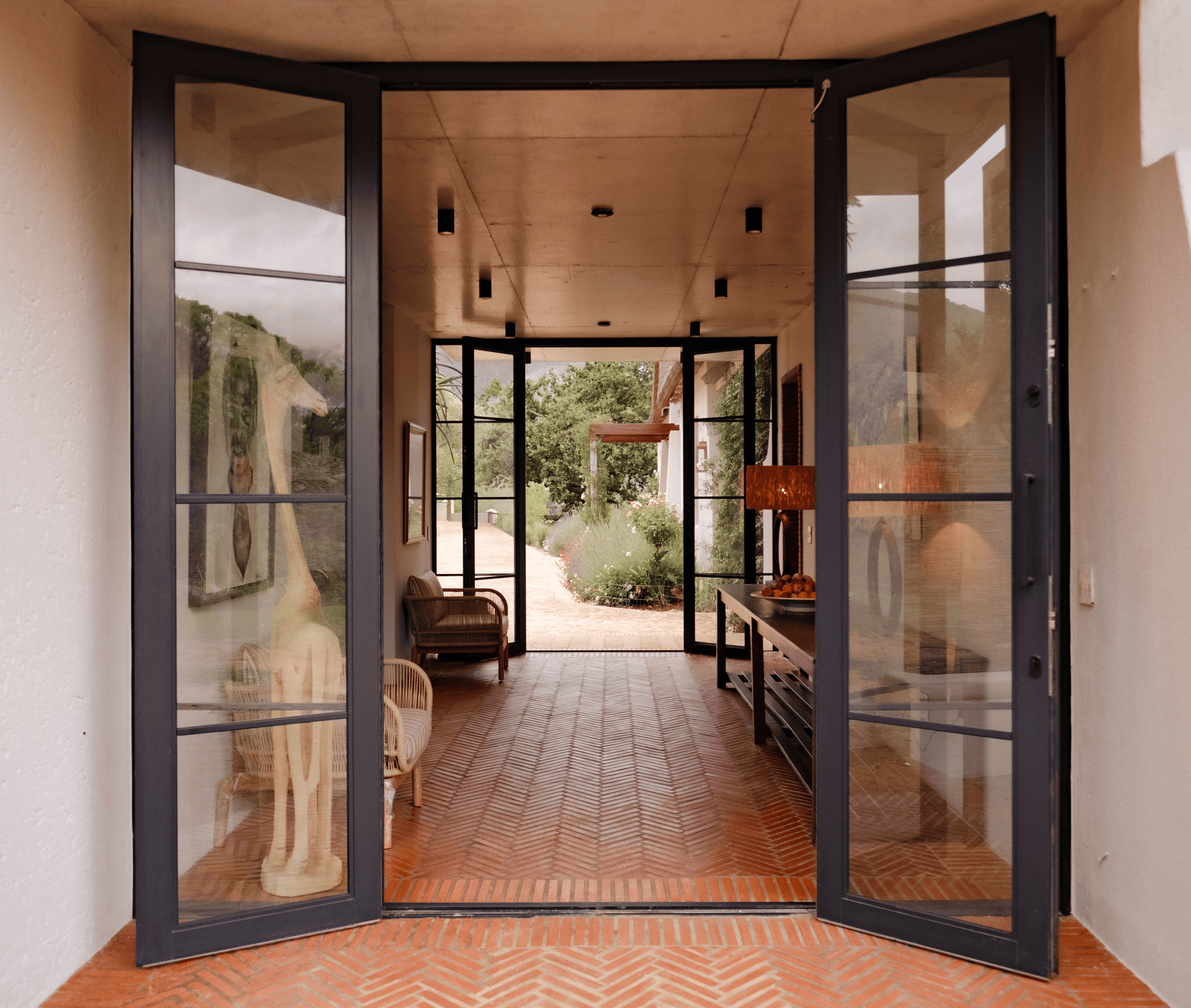 Open modern entryway with glass doors leading to a garden