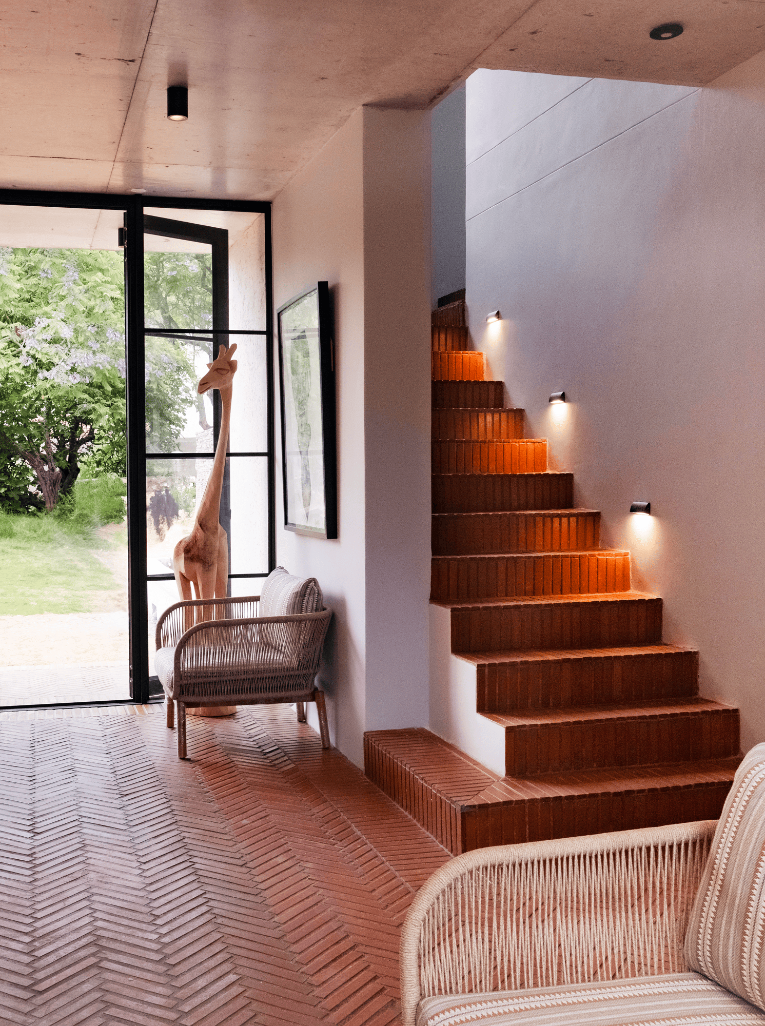 Modern home interior with brick staircase, giraffe sculpture, and outdoor view