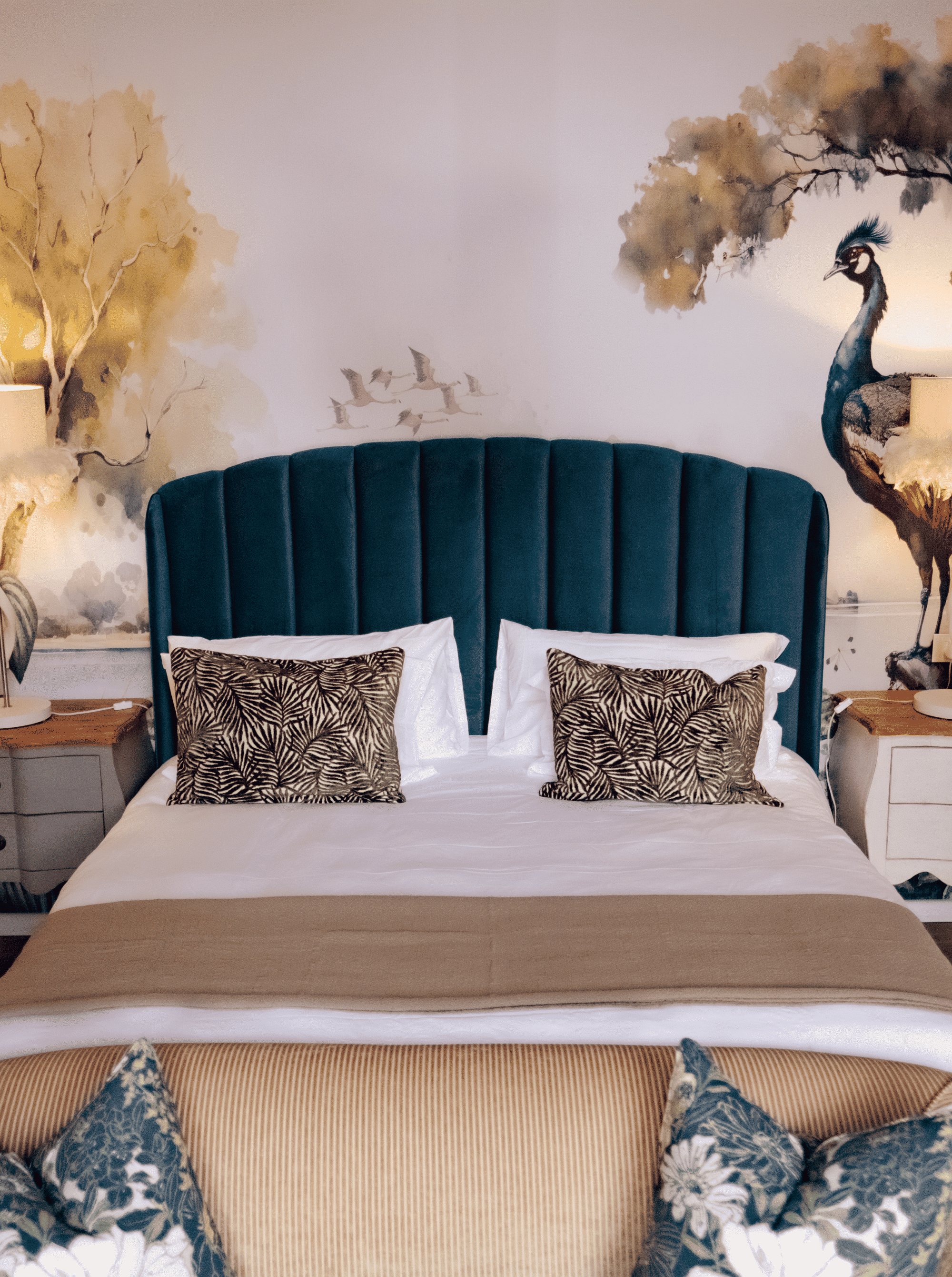 Stay with a Luxurious bedroom with a plush teal headboard and tropical bird mural