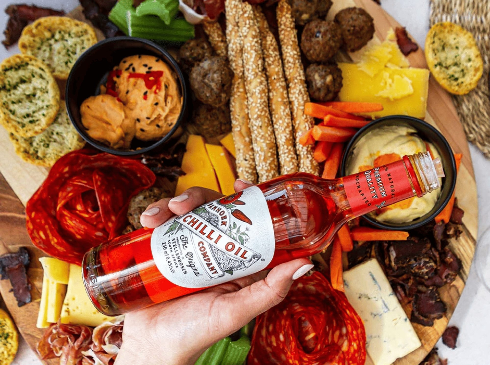 Charcuterie board with chili oil, cheese, meats, and dips