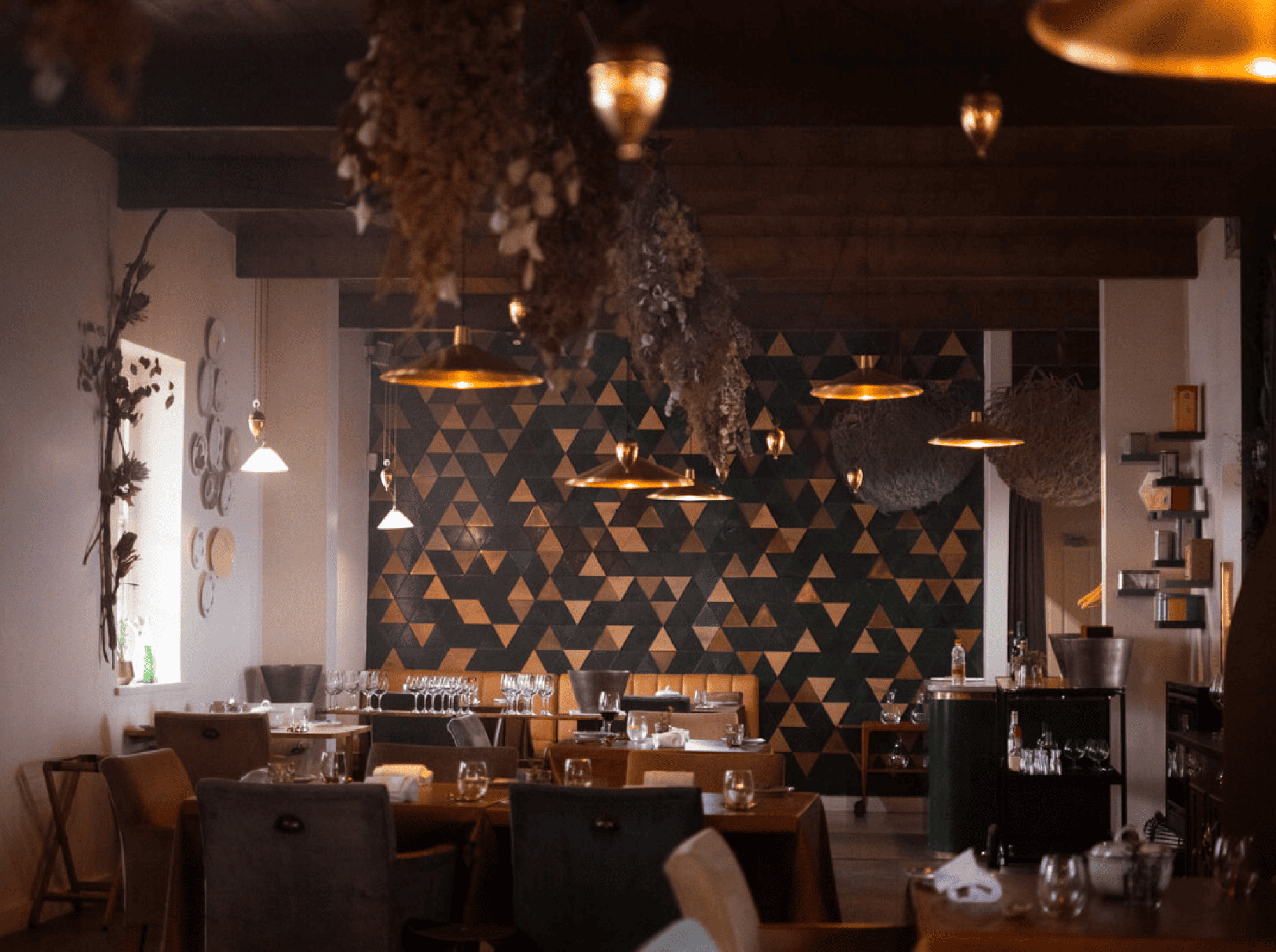 Elegant restaurant interior with geometric wall art and hanging plants, seen as you explore the Cape Winelands