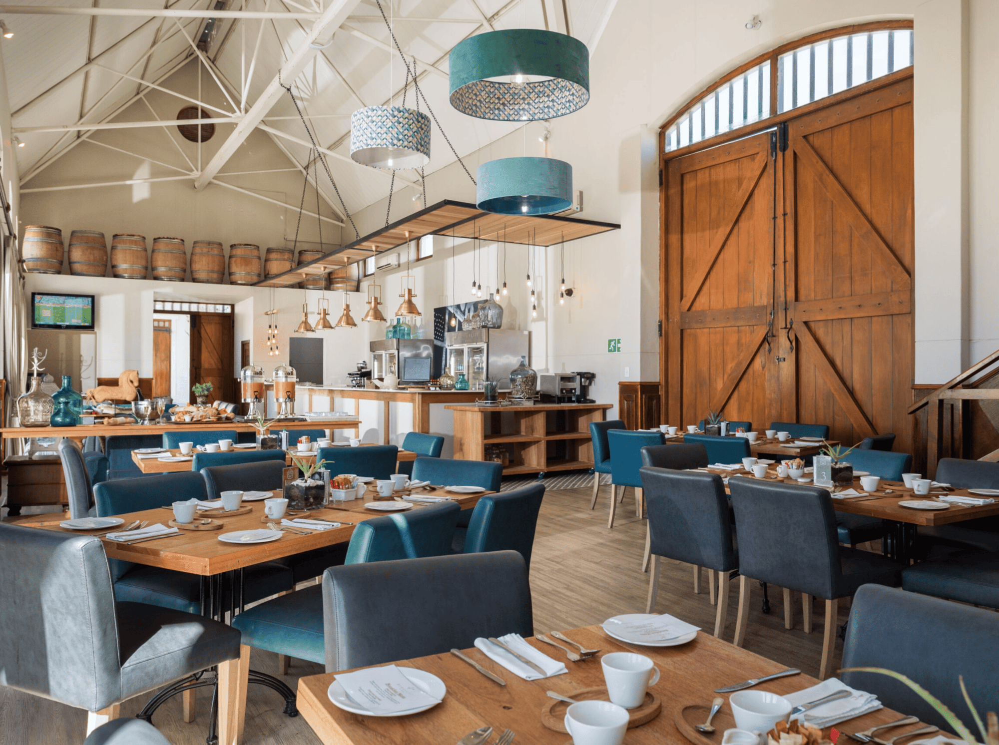 Elegant dining room with wooden tables, blue chairs, and large barn doors