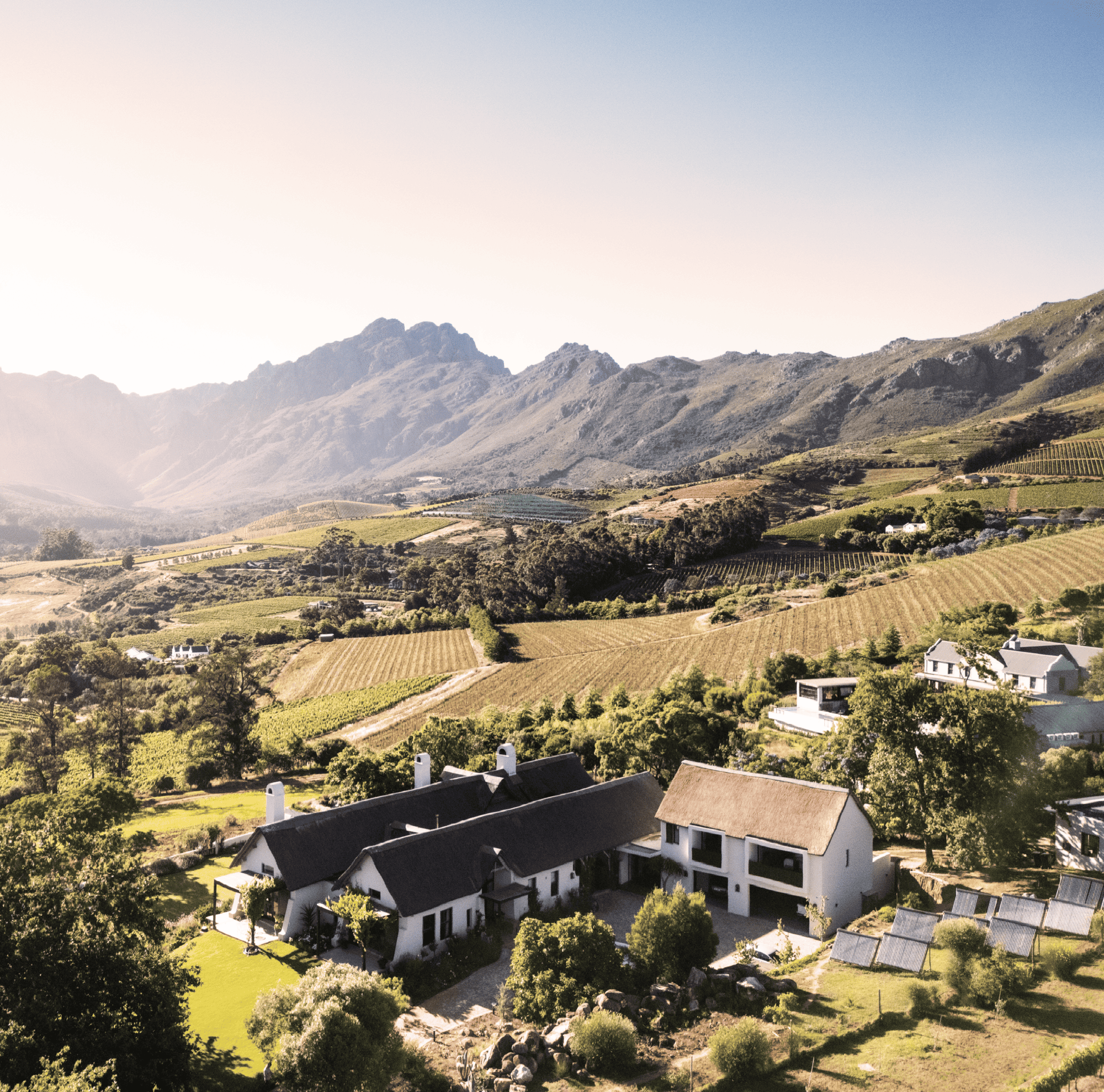 Vineyard estate with mountains in the background, featuring modern architecture and solar panels.